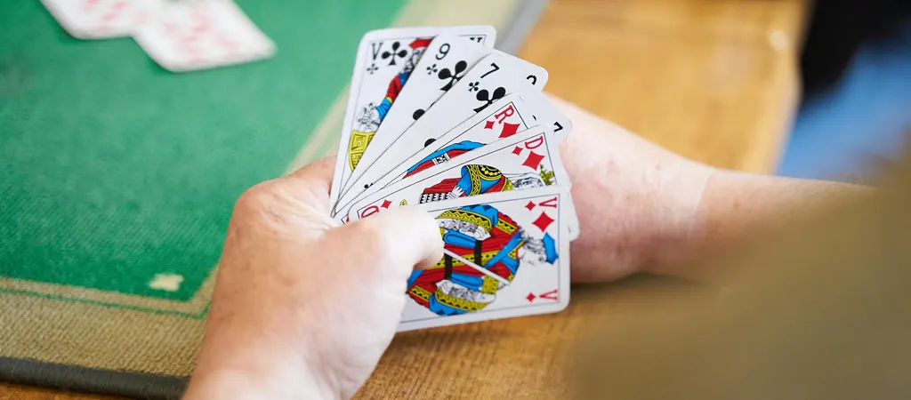 R&ouml;mi szab&aacute;lyok j&aacute;t&eacute;k menete, j&aacute;t&eacute;kos kez&eacute;ben k&aacute;rtyalapok z&ouml;ld asztalon