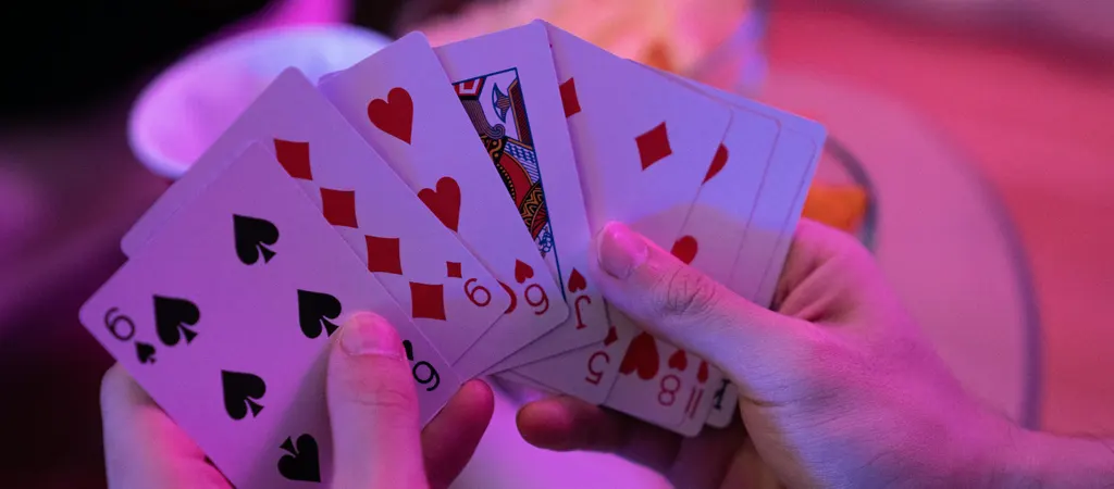 R&ouml;mi szab&aacute;lyzat pontoz&aacute;s, j&aacute;t&eacute;kos kez&eacute;ben k&uuml;l&ouml;nb&ouml;ző sz&iacute;nű k&aacute;rtyalapok l&aacute;that&oacute;k k&ouml;zelről