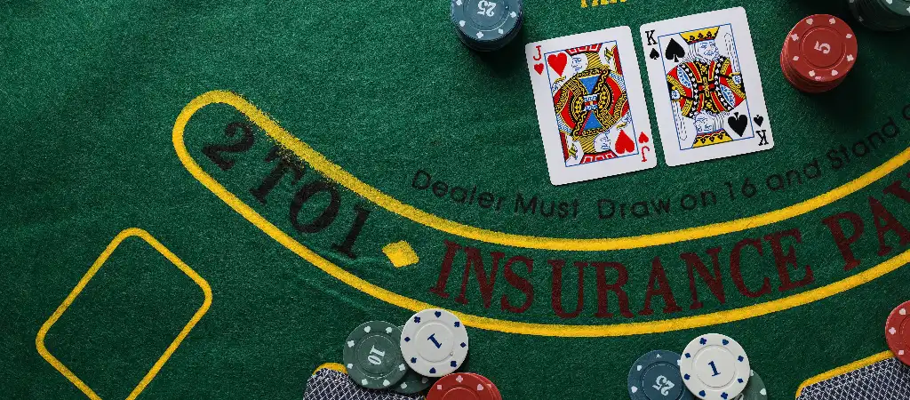 Blackjack szab&aacute;lyok kezdőknek, k&aacute;rty&aacute;k &eacute;s zsetonok az asztalon, a j&aacute;t&eacute;k alapjainak bemutat&aacute;sa kaszin&oacute; k&ouml;rnyezetben