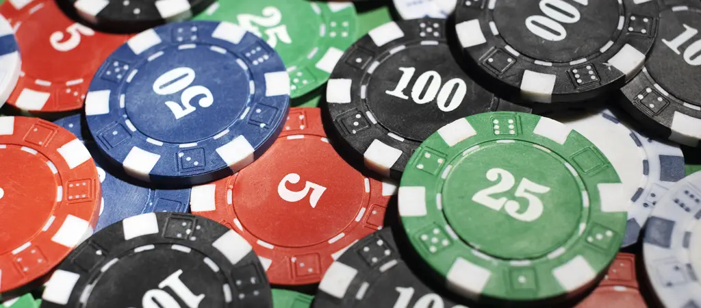 Nagy c&iacute;mletű zsetonok p&oacute;ker asztalon, bemutatva az &eacute;lő p&oacute;ker zseton &eacute;rt&eacute;kek kaszinokban haszn&aacute;lt rendszer&eacute;t
