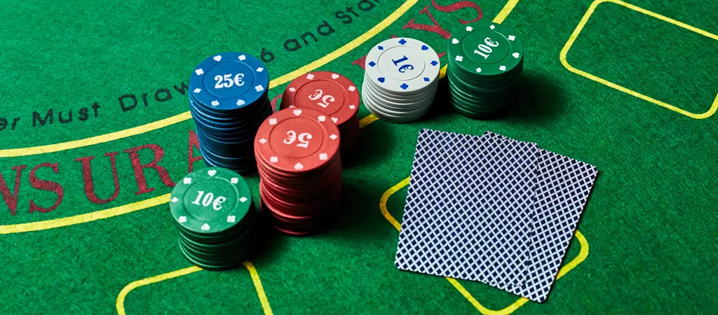 Black jack asztalon elhelyezett zsetonkupacok &eacute;s leford&iacute;tott lapok, amelyek seg&iacute;tenek meg&eacute;rteni, mit jelent a black jack strat&eacute;gia val&oacute;j&aacute;ban