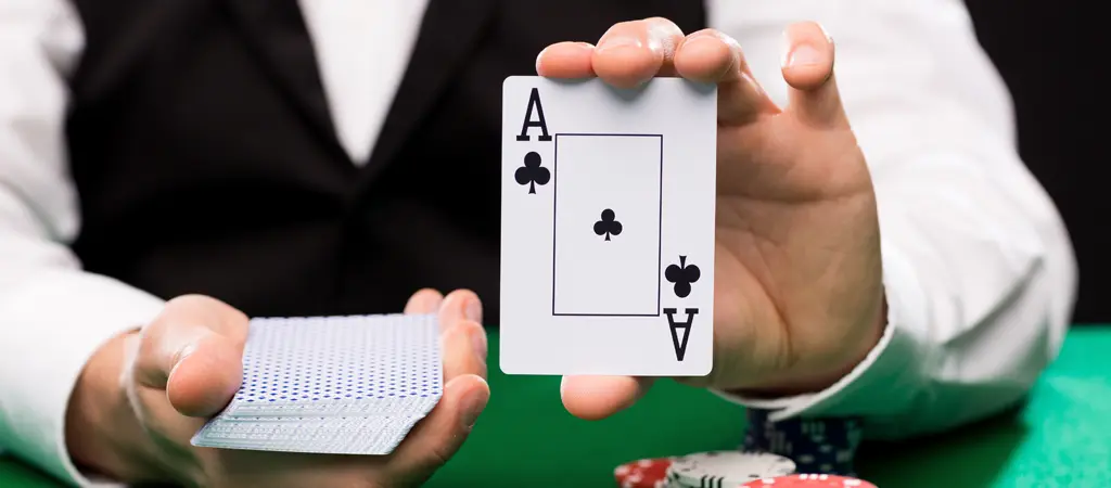 Oszt&oacute; kez&eacute;ben tartott &aacute;sz lap zsetonkupacok előtt, amely az online &eacute;lő black jack strat&eacute;gia d&ouml;nt&eacute;si helyzeteire utal