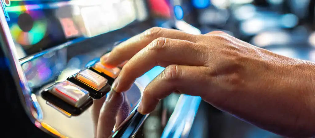 J&aacute;t&eacute;kos keze nyerőg&eacute;p ind&iacute;t&oacute;gombj&aacute;t nyomja meg k&ouml;zelről, amely a j&aacute;t&eacute;kos d&ouml;nt&eacute;seit &eacute;s az RTP &eacute;rt&eacute;k hat&aacute;s&aacute;t jelk&eacute;pezi a j&aacute;t&eacute;k sor&aacute;n